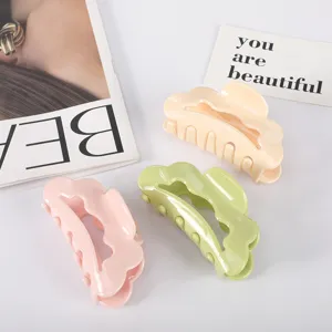 Close-up of large pastel acetate hair claw clips in pink, green, and cream colors
