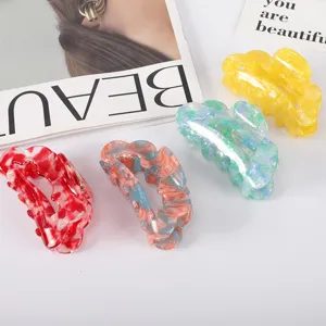Close-up of four colorful acetate marble patterned hair claw clips on fashion magazine