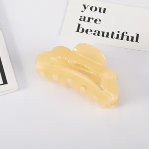 Detailed macro view of a creamy yellow acetate hair claw clip on a minimalist white background