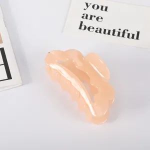 Detail view of an elegant peach acetate large hair claw clip in a minimalist style