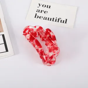 Close-up of large red marbled acetate hair claw clip with elegant fan-shaped design