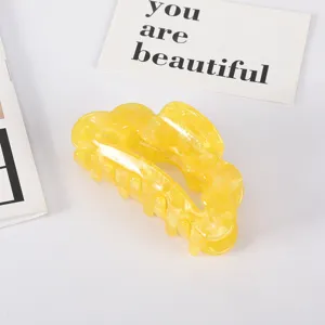 Detailed macro view showing the glossy texture of a yellow marble acetate hair claw clip