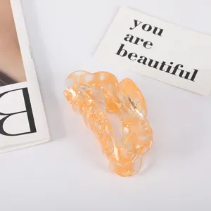 Detailed close-up view of a large amber acetate hair claw clip with marbled floral patterns