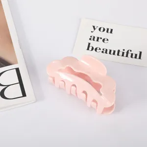 Close-up of a pink fan-shaped acetate hair claw clip with scalloped edges