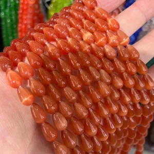 Close-up macro detail of 8x12mm orange teardrop cat-eye beads with vibrant chatoyancy