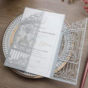 Elegante invitación de boda plateada cortada con láser y motivos florales dorados.