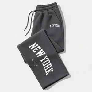 Detailed close-up of dark grey loose drawstring sweatpants with white letter prints.