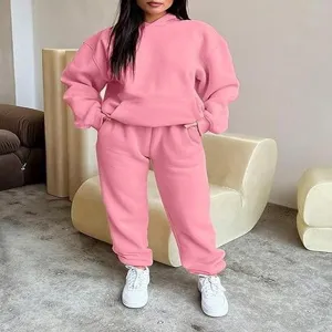 Detail shot of women casual pink hoodie and sweatpants tracksuit set in modern interior setting.