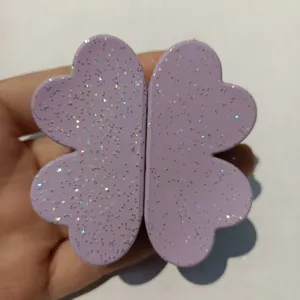 Close-up detail of a purple magnetic four-leaf clover hair clip with sparkling glitter surface.