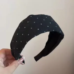 Detailed view of black cloth headband featuring white cross pattern, daily wide hair accessory.