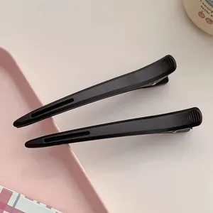 Professional black duckbill hair clips detail view, seamless sectioning clips for salon styling.