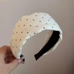 White padded headband with black cross print, stylish wide hair hoop for women daily wear.