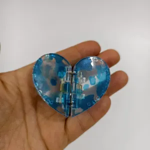 Nahaufnahme der blauen herzförmigen Magnet-Haarklammer mit Blick auf den Mechanismus.