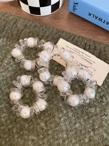 Elastici per capelli a spirale trasparenti con perle, dettaglio in primo piano di legacci telefonici.