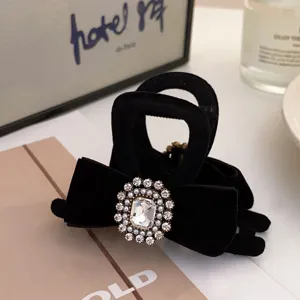 Detail shot of black velvet hair claw clip featuring elegant crystal rhinestone bow design.
