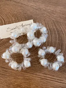 Primo piano dettagliato di elastici per capelli a filo telefonico trasparenti con perle bianche.