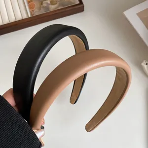 Close-up detail shot of wide PU leather headbands in black and khaki, clean aesthetic styling.