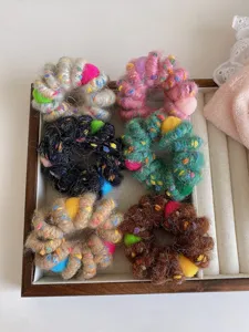 Detailed view of colorful plush telephone wire hair scrunchies with cute pom-pom balls.