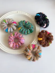 Close-up detail of colorful fuzzy telephone wire hair ties neatly arranged on a white plate.