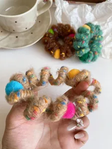 Plush phone cord hair tie with colorful pom-poms, stretchy and seamless for women.