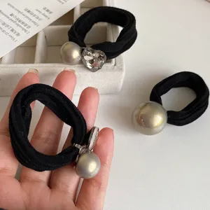 Vista dettagliata elastico capelli nero con grande perla grigia e ornamento cristallo a cuore brillante.