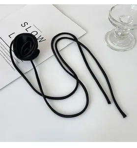 Collier choker rose en tissu noir chic avec longue lanière, élégant accessoire floral.