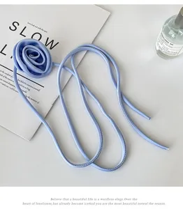 Gros plan sur le collier ras du cou en tissu bleu clair fleur de rose, accessoire floral.
