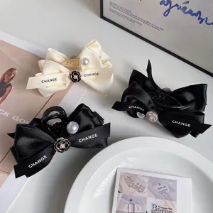 Satin bow hair claw clip with pearl and camellia flower design for elegant hairstyles.