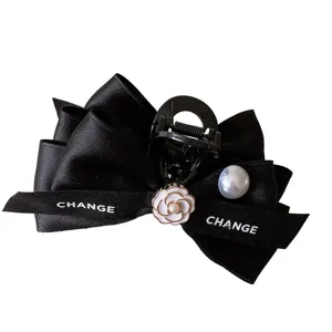 Black satin bow hair claw clip with camellia flower and pearl for elegant hair styling.