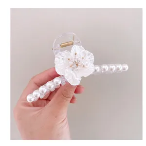 Primer plano detallado de la gran pinza para el pelo transparente con flor y perlas.