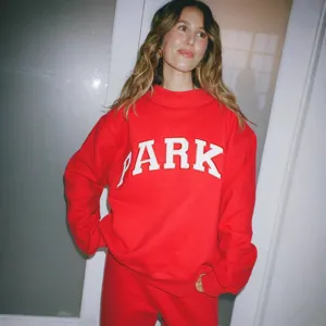 Red crewneck sweatshirt and pants set for women featuring bold PARK letter print.