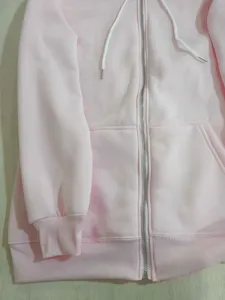 Close up of pink zip hoodie detail, featuring smooth metal zipper and soft ribbed fabric.