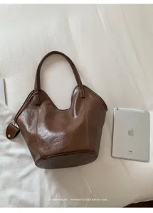 Detail view of a minimalist brown retro tote bag placed on a white fabric surface