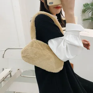Detail shot of a soft plush camel-colored underarm bag worn by a stylish model