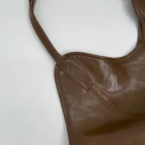 Detailed close-up of brown vintage leather tote bag stitching and strap attachment