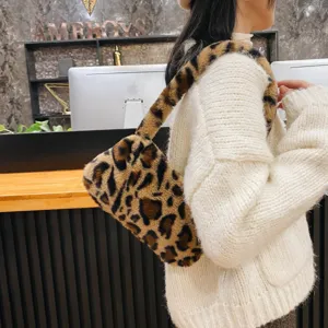 Detailed close-up of a stylish plush leopard print underarm bag worn with a knit sweater.