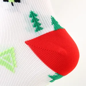 Detail von weißen Weihnachts-Kompressionssocken mit grünem Baummuster und roter Ferse