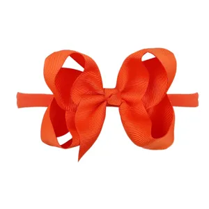 Detailed macro view of a vibrant orange grosgrain ribbon bow headband for baby girls.