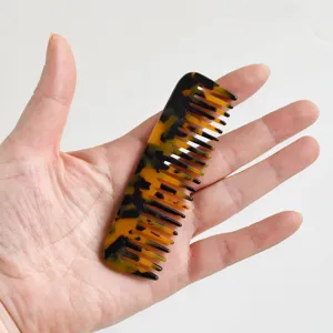 Pettine portatile a denti larghi in acetato tartarugato tenuto in una mano aperta
