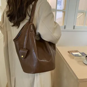Macro view of a large retro brown faux leather tote bag being worn on the shoulder