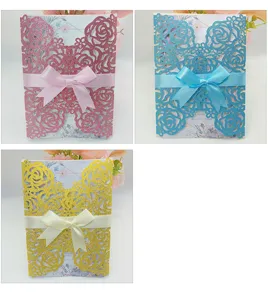 Detailed view of laser-cut rose wedding invitations in pink blue and gold with ribbon bows