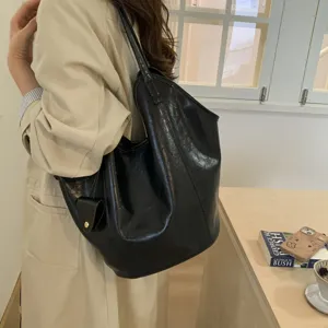 Detail of a woman wearing a black glossy leather vintage tote bag with large capacity