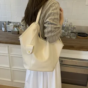 Large capacity cream minimalist tote bag worn by a model in a cozy kitchen setup