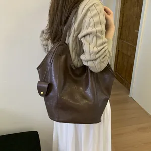 Detailed view of large vintage brown faux leather tote bag on model's shoulder