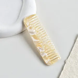 Dettaglio macro di un elegante pettine a denti larghi in acetato con trama marmorea