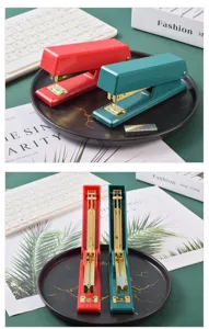 Detailed view of luxury red and green office staplers with gold interior for effortless binding.