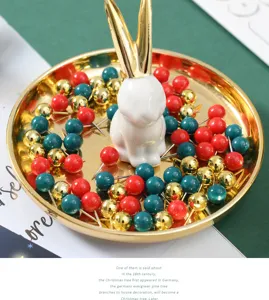 Detaillierte Nahaufnahme von bunten Pinnnadeln in einer goldenen Schale mit Hasen.