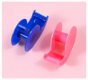 Gros plan de dévidoirs de ruban adhésif miniatures en plastique bleu et rose.