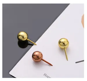 Nahaufnahme von metallischen kugelförmigen Reißzwecken in Gold und Roségold für Pinnwände.