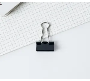 Vue détaillée d'une pince à dessin métallique noire sur papier quadrillé pour documents.
